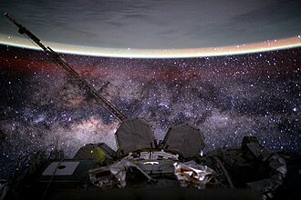 A view from the International Space Station, in a low Earth orbit (LEO) at about 400 km (250 mi), with yellow-green airglow visible at Earth's horizon, where roughly at an altitude of 100 km (62 mi) the boundary between Earth and outer space lies and flying speeds reach orbital velocities