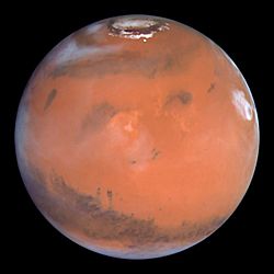 Hubble view of Mars: Gale crater can be seen. Slightly left and south of center, it is a small dark spot with dust trailing southward from it.
