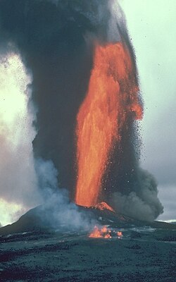 Molten lava fountain at Kilauea volcano on Hawaii, with black cloud of associated tephra