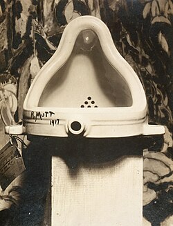 Marcel Duchamp Fountain, 1917, photograph by Alfred Stieglitz at 291 (art gallery) following the 1917 Society of Independent Artists exhibit, with entry tag visible. The backdrop is The Warriors by Marsden Hartley.[5]