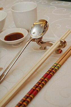 Photo showing serving chopsticks (gongkuai) on the far right, personal chopsticks (putongkuai) in the middle, and a spoon. Serving chopsticks are usually more ornate than the personal ones.