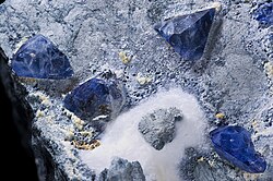 Benitoite crystals on natrolite. The mineral is named for the San Benito River in San Benito County where it was first found.