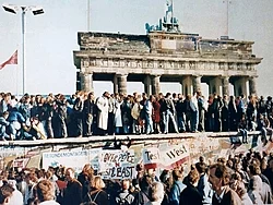People standing on top the Berlin Wall during its fall in 1989 in front of the Brandenburg Gate