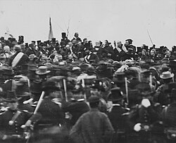 On November 19, 1863, President Abraham Lincoln (center, facing camera) traveled to present-day Gettysburg National Cemetery and delivered the Gettysburg Address, a 271-word address considered one of the most famous speeches in American history.[57][58]